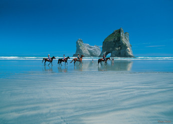 Horses and riders on Wharariki Beach in the Nelson-Tasman region of the South Island of New Zealand